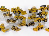 de nombreux engins de chantier miniatures exposés sur une surface blanche