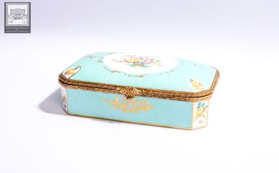 une petite boîte bleue ornée d'une bordure dorée et d'une fleur