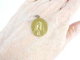a woman ' s hand holding a gold coin with a dog on it