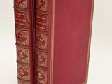 two red books sitting on top of each other on a white surface