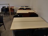 des tables et des chaises dans une pièce vide, avec un projecteur en arrière-plan