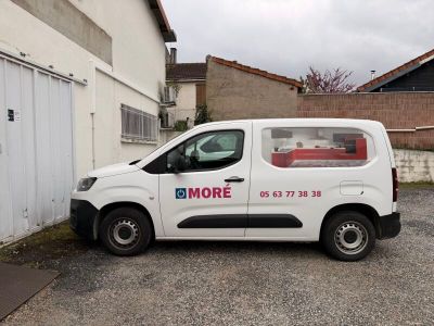 une petite camionnette blanche garée devant un bâtiment