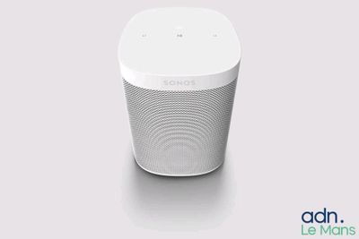 a white speaker sitting on top of a table next to a wall