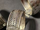 three silver bracelets with designs on them sitting next to each other