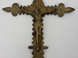 un gros plan d'une croix accrochée à un mur, sur laquelle se trouve une personne