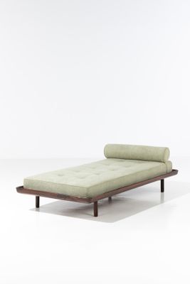 une chaise longue verte posée sur un sol blanc