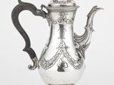 une cafetière ancienne en argent avec une poignée noire sur fond blanc
