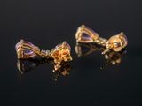 pair of gold and amethorate bow earrings on a black surface