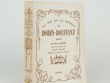 un vieux livre posé sur une table blanche à côté d'un mur blanc