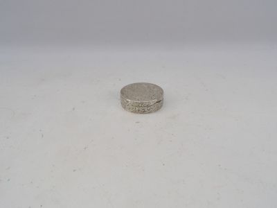 a small silver coin sitting on top of a white surface
