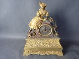 une horloge en or avec une femme assise dessus