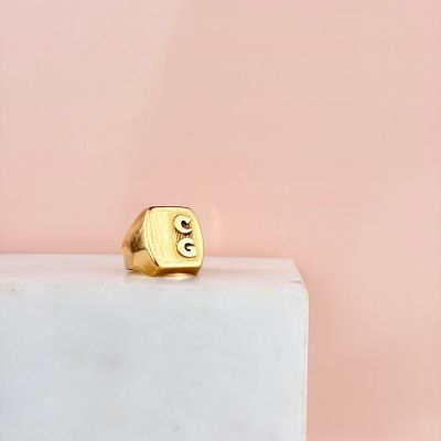 un gros plan d'une bague en or posée sur un bloc de marbre