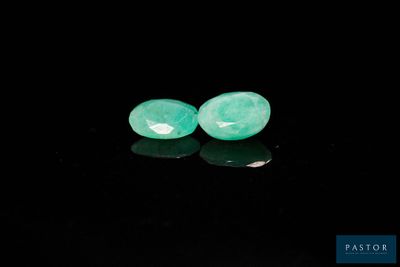 une paire de perles de jade vert sur un fond noir