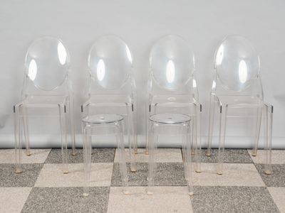 trois chaises en plastique transparent placées les unes à côté des autres sur un sol à carreaux