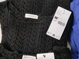 three black sweaters with price tags on them sitting on a table
