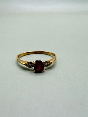 a close up of a gold ring with a red stone on it