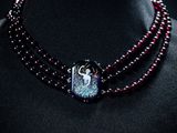 Collier de perles violettes et noires orné d'un pendentif en forme d'oiseau, porté par un mannequin