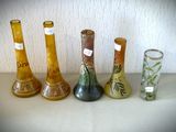 cinq vases différents posés sur une table, sur lesquels sont apposées des étiquettes