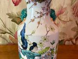 un vase blanc orné d'oiseaux, posé sur une table