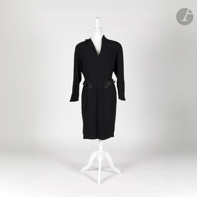 une robe noire posée sur un support de mannequin, avec un mannequin blanc