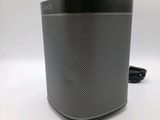 a black speaker sitting on top of a table next to a charger