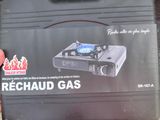 une valise noire sur laquelle est posé un réchaud bleu