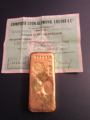 un lingot d'or posé sur une feuille de papier, à côté d'un ticket de caisse