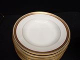 a stack of white plates with gold trims on a black table