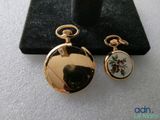 a gold pocket watch and a pair of earrings on display