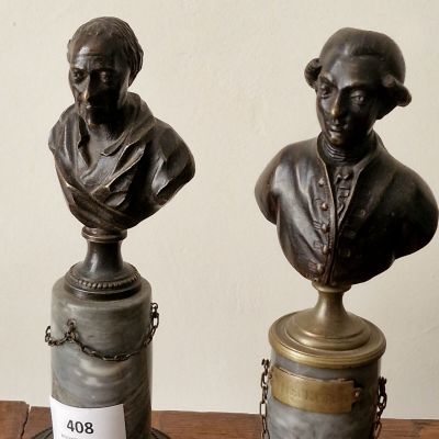 deux petits bustes en bronze représentant un homme et une femme, posés sur une table