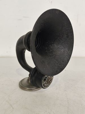 une corne noire posée sur une table blanche, sur fond blanc