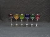 six different colored wine glasses are lined up in a row