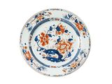 an orange and blue plate with a bird and flowers on it