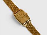 a close up of a gold watch on a white surface