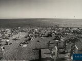 black and white photo of people on a beach with umbrellas