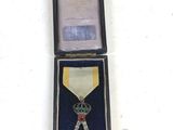 a medal in a case with a dice and a piece of paper