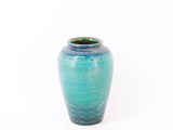un vase bleu posé sur une surface blanche