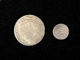 two silver coins sitting next to each other on a black surface
