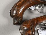 pair of antique flinted pistols on a table with tags attached to them