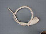 a white object with a white cord attached to it next to a cup