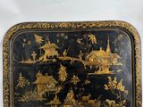 a black and gold tray with a painting on it
