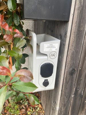 une boîte blanche avec un bouton noir sur le côté d'une clôture