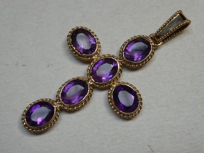 a close up of a cross with purple stones on it