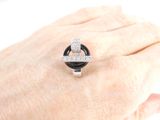 a woman ' s hand holding a ring with a diamond on it