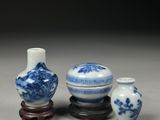 three blue and white vases sitting on top of a wooden stand