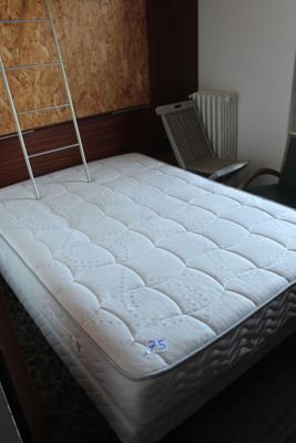 un matelas posé à même le sol dans une pièce où se trouve une échelle