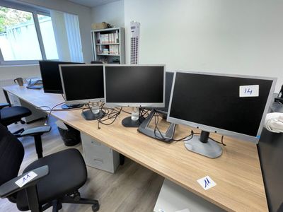 trois écrans d'ordinateur posés sur un bureau dans un bureau
