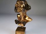 une statue en or représentant un homme portant un chapeau et un nœud papillon
