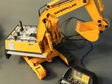 a yellow excavator that is sitting next to a remote control