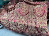 une couverture rouge et dorée posée sur une chaise dans une pièce